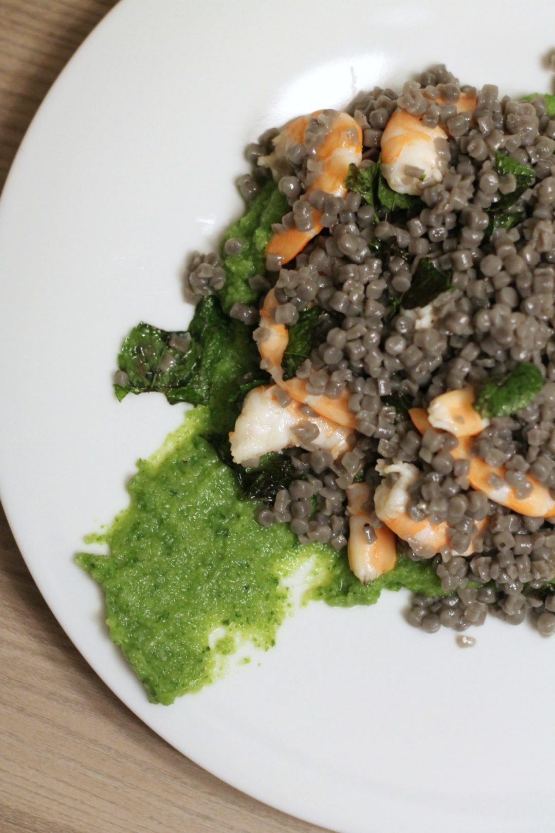 Fregola al nero di seppia con crema di zucchine e gamberi alla menta